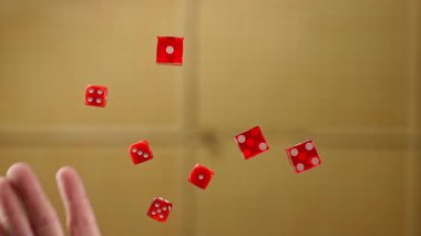 Yumuşak bir bej arka planda süzülürken yakalanan kırmızı zarlar. Görüntü dinamik ve çekici. Yavaş çekim