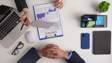 İşbirlikçi bir iş toplantısında bir sözleşmeyi gözden geçirme ve bilgilendirilmiş karar verme için veri tablolarını analiz etme üzerinde duruldu. Üst çekim