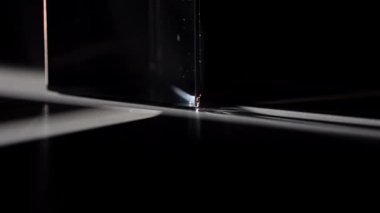 Açık bir prizma büyüleyici ışık ve gölge desenleri oluşturarak büyüleyici bir optik etki yaratıyor. Macro, ağır çekim.