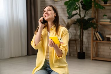 Bir kadın valizini toplar ve akıllı telefonuyla seyahate ya da tatile hazırlanırken konuşur..