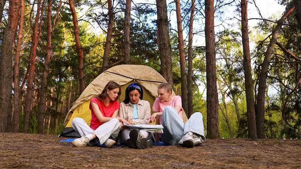 Üç arkadaş ormanda kamp yaparken heyecan verici bir an yaşadılar, bir çadırın etrafında toplandılar..