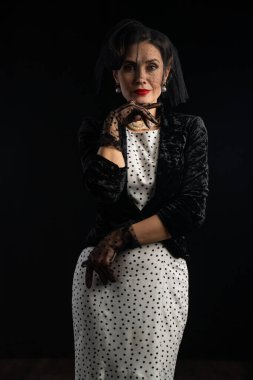 Klasik bir portre klasik modanın zamansız zarafetini yakalıyor, şık bir siyah kadife ceket ve ince bir peçeyle beyaz benekli elbise..