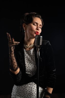 Şık bir kadın klasik caz sanatçılarının zarafetini somutlaştıran klasik bir mikrofona tutkuyla şarkı söylüyor..