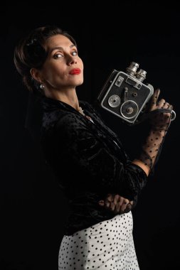 Klasik bir film kamerası taşıyan zarif bir kadın, zamansız cazibe ve stili somutlaştırıyor..