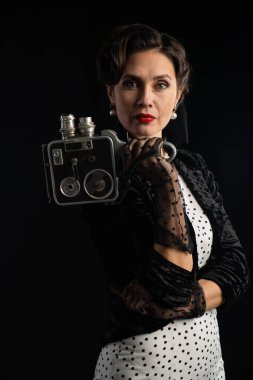 Bir kadın, bu sofistike geçmişe dönük portrede eski model bir fotoğraf makinesini tutarken zarafet yayar..