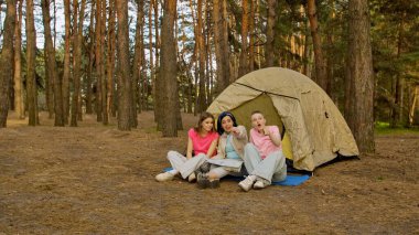 Üç arkadaş ormanda kamp yaparken heyecan verici bir an yaşadılar, bir çadırın etrafında toplandılar..