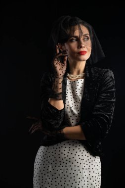 Puantiyeli elbise ve siyah peçe takan göz kamaştırıcı bir kadın. Çok zarif ve sofistike..