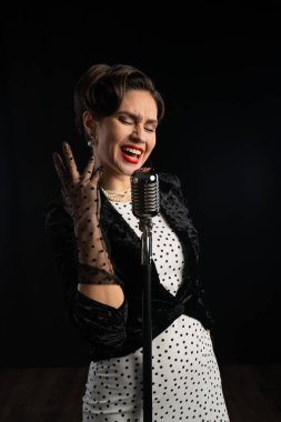 Eski tarz bir sanatçı, eski moda bir mikrofona tutkulu bir şekilde şarkı söyler. Zarif kıyafetler giyer, eski bir müzik ve tarz dönemini hatırlatır..