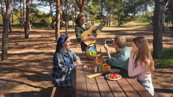 Bir grup arkadaş piknik için toplanır, güneşli bir açık hava ortamında yemek ve müziğin tadını çıkarırlar, rahatlamayı teşvik ederler..