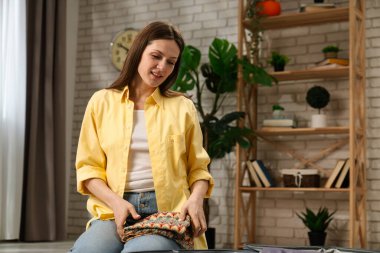 Bir kadın düşünceli bir şekilde giysilerini bavula koyup yolculuğa hazırlanıyor. Oda modern ve rahat..