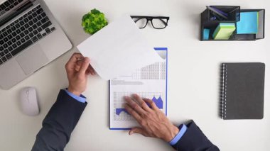Dizüstü bilgisayar, sözleşme belgeleri, çizelgeler, not defterleri ve iş verimliliğini sembolize eden bir kahve fincanı içeren profesyonel bir çalışma alanı. Üst çekim