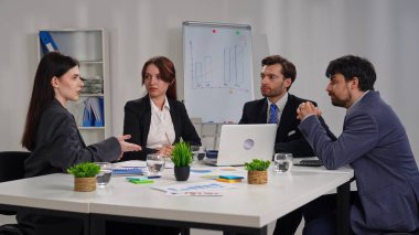 Ofiste bir iş toplantısına katılan dört profesyonel, çizelgelerle stratejiyi tartışıyor..