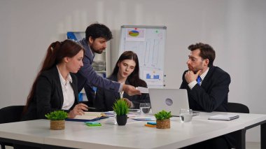 Ofiste bir iş toplantısına katılan dört profesyonel, çizelgelerle stratejiyi tartışıyor..