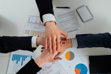 İş grafikleri üzerinde takım çalışması jestine katılan bir grup el işbirliği ve birliği sembolize ediyor