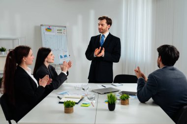 Bir iş toplantısı sırasında bir takımın alkış tutması, başarı ve işbirliğini sembolize ediyor..