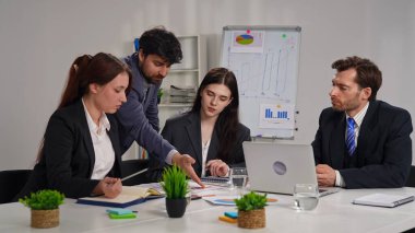 Ofiste bir iş toplantısına katılan dört profesyonel, çizelgelerle stratejiyi tartışıyor..