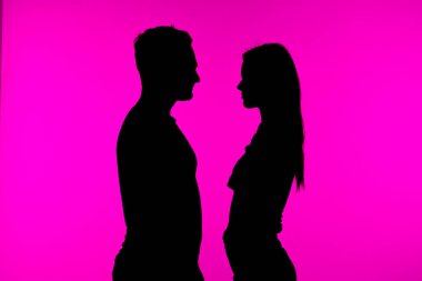 Bir çift silueti, canlı kırmızı bir arkaplan karşısında romantik bir ortam yaratıyor..