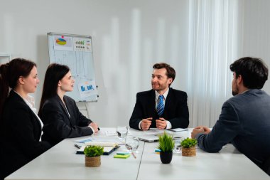 Ofiste bir iş toplantısına katılan dört profesyonel, çizelgelerle stratejiyi tartışıyor..