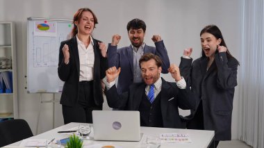 Modern ofis ortamında başarılı bir dönüm noktasını kutlayan resmi giyinmiş bir grup profesyonel..