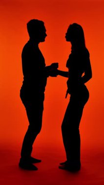 Parlak kırmızı arka planda dans eden bir çiftin silüeti.