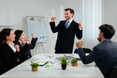Modern ofis ortamında başarılı bir dönüm noktasını kutlayan resmi giyinmiş bir grup profesyonel..
