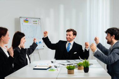 Modern ofis ortamında başarılı bir dönüm noktasını kutlayan resmi giyinmiş bir grup profesyonel..