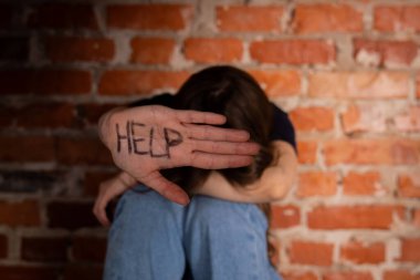 Tuğla duvarın karşısında oturan bir şahıs üzerinde 