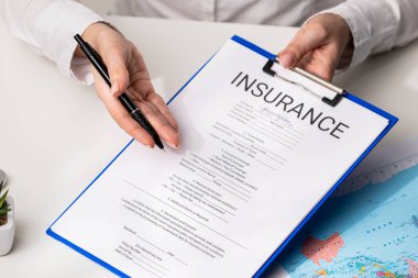 Ofiste seyahat sigortası formunu belgelemek, ajanların ellerini kapatmak. Bir kişi, bilginin doğruluğu ve eksiksizliğine odaklanan bir sigorta belgesini inceler ve imzalar.