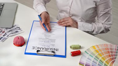 Bir sigorta acentesi ve bir müşteri ofiste dikiş malzemeleri sigorta belgesi imzalarlar. Sigorta ve iş koruması.