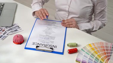 Sigorta acentesi ofiste dikiş malzemeleri sigorta belgesini imzalıyor. Sigorta ve iş koruması.