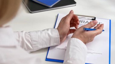 Sigorta belgesinin yanında elinde kalem tutan bir kişinin yakın plan fotoğrafı, önemini vurgulamak için. Ofiste sigorta formunu belgelemek.