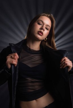 Modaya uygun bir kadın koyu renk bir elbiseyle modern zarafeti ve cesur stili ön plana çıkarıyor. Moda yazıları, giyim markaları veya aksesuar reklamları için..