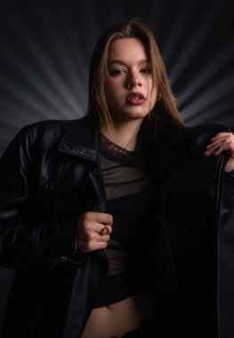 Bir kadın kendine güvenen siyah deri bir ceket ve katıksız bir bluzla poz verir. Tarz ve tutum duygusu yayar. Moda yazıları, giyim markaları veya aksesuar reklamları için..