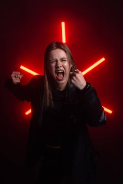 Şiddetli kızgınlığını ifade eden cesur bir kırmızı ışık arka planıyla vurgulanmış, ham duygu aktaran bir kişi. Moda yazıları, giyim markaları veya aksesuar reklamları için..