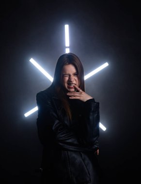 Siyah deri ceketli biri arka planda neon ışıklarla poz verip dramatik ve şık bir görünüm yaratıyor. Moda yazıları, giyim markaları veya aksesuar reklamları için..