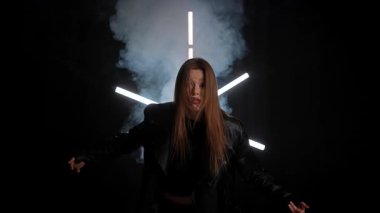 Siyah deri ceketli biri arka planda neon ışıklarla poz verip dramatik ve şık bir görünüm yaratıyor. Moda yazıları, giyim markaları ya da aksesuar reklamları için. Yavaş çekim.