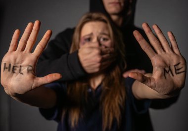 Aile içi şiddet durumlarında acil yardım çağrısını vurgulayan, korku ve savunmasızlığı vurgulayan bir görsel ekran.