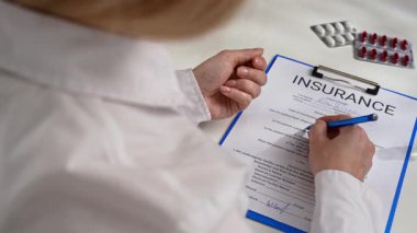 Bir hastanenin ya da sigorta acentesinin ofisindeki hayat ve sağlık sigortası formunu belgelemek. Bir kişi sigorta formunu kalemle dikkatlice doldurur. Detaylara dikkat ve hassasiyet sağlar..