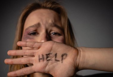 Aile içi şiddet karşısında yardım çağrısını vurgulayan güçlü bir görüntü, acil farkındalık ve destek ihtiyacını vurguluyor.