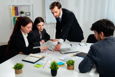 Ofiste bir iş toplantısına katılan dört profesyonel, çizelgelerle stratejiyi tartışıyor..