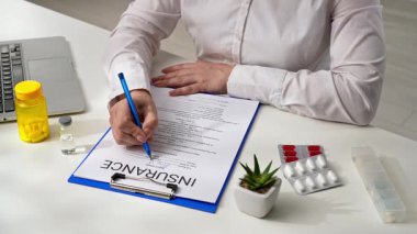 Bir hastanenin ya da sigorta acentesinin ofisindeki hayat ve sağlık sigortası formunu belgelemek. Bir kişi sigorta formunu kalemle dikkatlice doldurur. Detaylara dikkat ve hassasiyet sağlar..