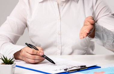 Beyaz gömlekli bir profesyonel iş formalitelerini vurgulayan bir belge imzalamaya hazırlanıyor. Ofiste seyahat sigortası formunu belgelemek.