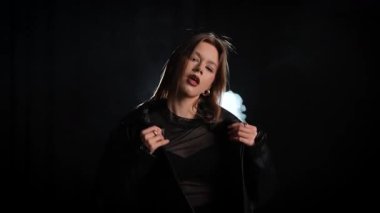 Siyah deri ceketli bir kadın koyu bir arka plana karşı özgüvenle poz verir, zarafet ve tarz yayar. Moda yazıları, giyim markaları veya aksesuar reklamları için..