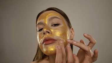 Genişletici cilt bakımı için parıldayan altın bir maske takan bir kadının yakın çekimi..