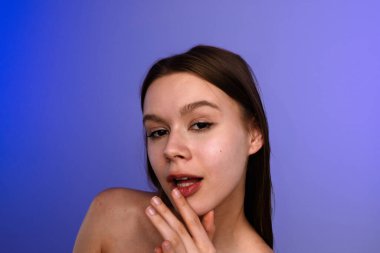 Zarif bir mavi arka plana karşı düşünceli bir ifadeyle poz veren bir kadın zarif bir sadelik yakalıyor..