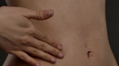 Bir kadın eli karnına krem sürüyor.