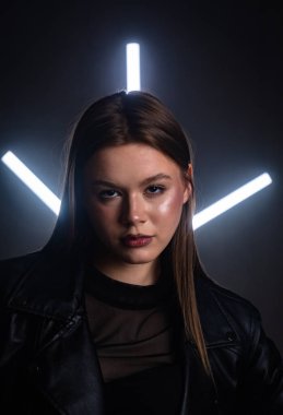 Siyah deri ceketli bir kadının büyüleyici portresi. Neon ışıkları çarpıcı bir arka plan yaratır. Moda yazıları, giyim markaları veya aksesuar reklamları için..