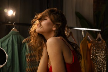 Genç bir kadın soyunma odasında hazırlanıyor. Nazikçe aydınlatarak düşünceli ifadesini vurguluyor..