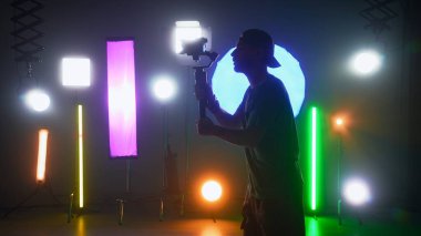 Sahne arkasında. Işıklandırma ekipmanlarıyla profesyonel atış alanı. Bir müzik videosu çekme süreci. Operatör kameraya video çekiyor.