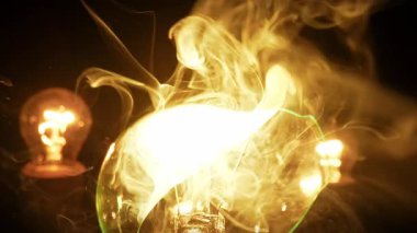 Tungsten ampulü aşırı ısınır, patlar ve siyah arka planda cam kırılır. Modern evde aydınlık ve karanlık, tehlike ve elektrik kavramı